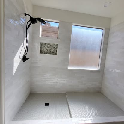 Large walk-in shower with pale tile, bench and recessed niche