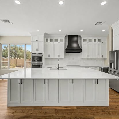 Completed bright white kitchen with large island and wood flooring
