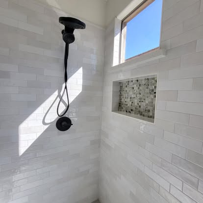Close detail of shower tile, fixture plumbing and mosaic niche